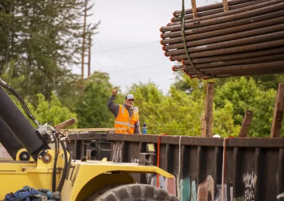 Employee guiding unloading of cap steel pipes