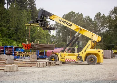 Reach stacker lowering cap steel pipes onto yard